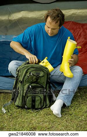 High angle view of a mature man packing galoshes into a backpack View Large Photo Image Stock Photo - High angle view of a mature man packing galoshes into a backpack. Fotosearch