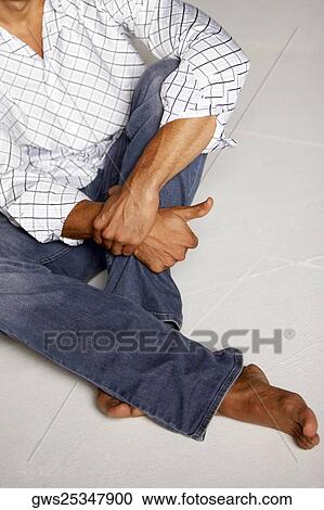 Stock Image - High angle view of a mid adult man sitting on the floor. Fotosearch