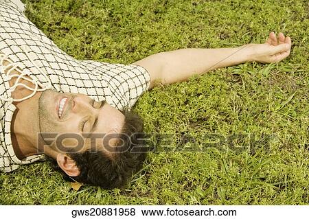 Stock Photo - High angle view of a mid adult man sleeping on the grass. Fotosearch