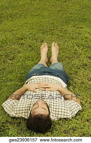 Stock Photo - High angle view of a mid adult man sleeping on the grass. Fotosearch