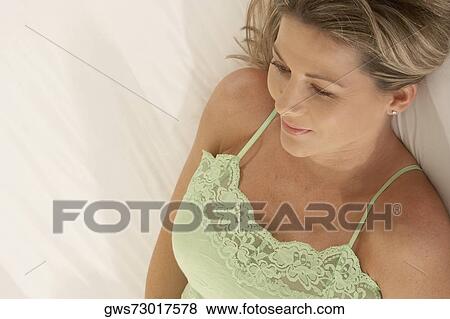 Stock Photo - High angle view of a mid adult woman lying on the bed. Fotosearch