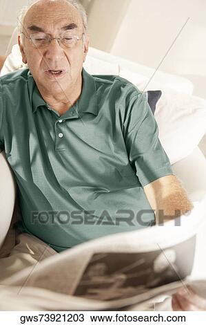 High angle view of a senior man reading a newspaper View Large Photo Image Stock Image - High angle view of a senior man reading a newspaper. Fotosearch