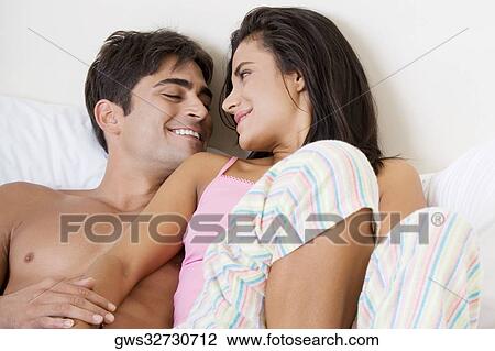 Stock Image - High angle view of a young couple lying on the bed. Fotosearch