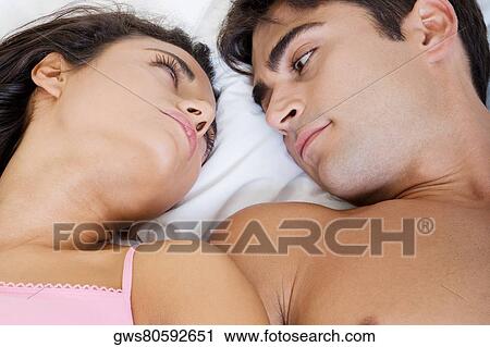 High angle view of a young couple lying on the bed looking at each other View Large Photo Image Stock Image - High angle view of a young couple lying on the bed looking at each other. Fotosearch