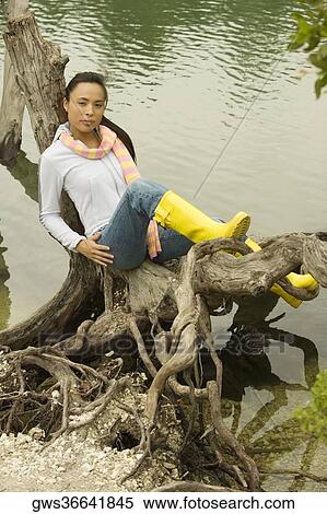 High angle view of a young woman sitting on a tree trunk by the lake View Large Photo Image Stock Photography - High angle view of a young woman sitting on a tree trunk by the lake. Fotosearch