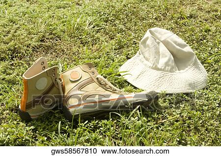 Stock Image - High angle view of pair of shoes with a hat on the grass. Fotosearch