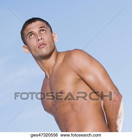 Low angle view of a bare chested young man looking up View Large Photo Image Stock Photograph - Low angle view of a bare chested young man looking up. Fotosearch