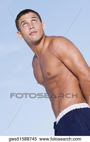 Low angle view of a bare chested young man looking up View Large Photo Image Stock Photography - Low angle view of a bare chested young man looking up. Fotosearch