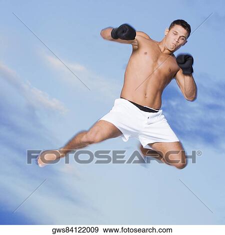 Low angle view of a young man in a fighting stance View Large Photo Image Stock Photo - Low angle view of a young man in a fighting stance. Fotosearch
