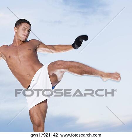 Low angle view of a young man kicking View Large Photo Image Stock Image - Low angle view of a young man kicking. Fotosearch
