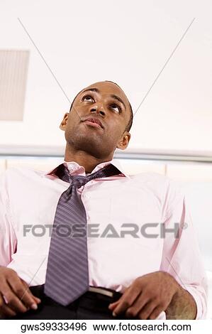 Low angle view of a young man looking away View Large Photo Image Stock Photograph - Low angle view of a young man looking away. Fotosearch