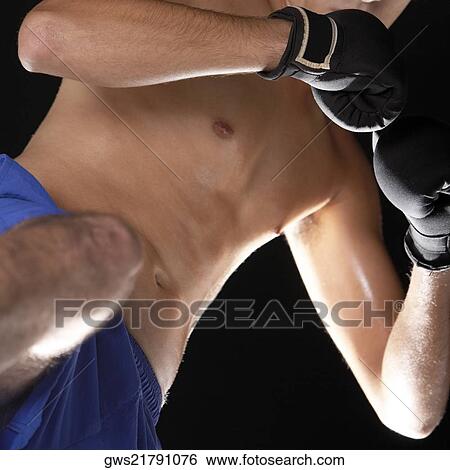 Low angle view of a young man wearing boxing gloves View Large Photo Image Stock Photograph - Low angle view of a young man wearing boxing gloves. Fotosearch