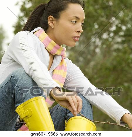 Low angle view of a young woman holding a stick View Large Photo Image Stock Photography - Low angle view of a young woman holding a stick. Fotosearch