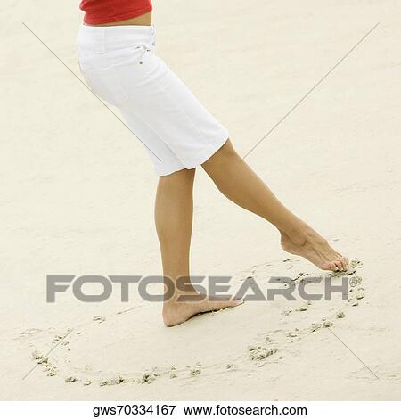 Low section view of a girl drawing in sand with her toe View Large Photo Image Stock Photo - Low section view of a girl drawing in sand with her toe. Fotosearch