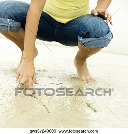Low section view of a girl writing in sand with her finger View Large Photo Image Stock Image - Low section view of a girl writing in sand with her finger. Fotosearch