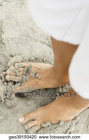 Stock Image - Low section view of a man standing on the beach. Fotosearch