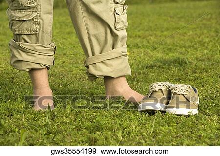 Stock Photo - Low section view of a mid adult man standing on the grass. Fotosearch