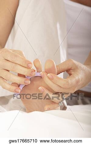 Low section view of a mid adult woman adjusting her toenail divider View Large Photo Image Stock Image - Low section view of a mid adult woman adjusting her toenail divider. Fotosearch