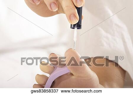 Low section view of a mid adult woman applying nail polish on her toenails View Large Photo Image Stock Photo - Low section view of a mid adult woman applying nail polish on her toenails. Fotosearch