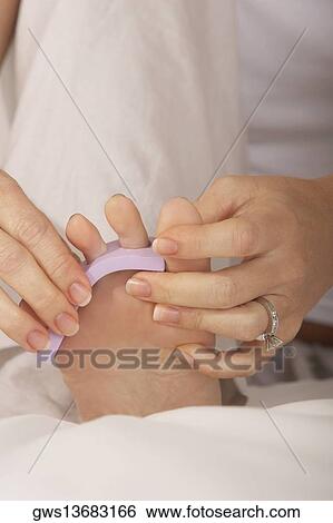 Low section view of a mid adult woman adjusting her toenail divider View Large Photo Image Stock Photograph - Low section view of a mid adult woman adjusting her toenail divider. Fotosearch