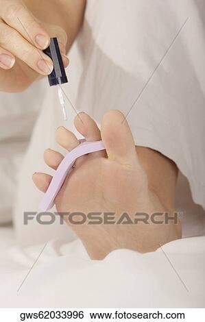 Low section view of a mid adult woman applying nail polish on her toenails View Large Photo Image Stock Photograph - Low section view of a mid adult woman applying nail polish on her toenails. Fotosearch