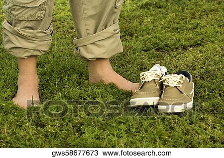 Low section view of a person standing near a pair of canvas shoe View Large Photo Image Stock Image - Low section view of a person standing near a pair of canvas shoe. Fotosearch