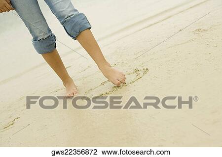 Low section view of a woman drawing in sand with her toe View Large Photo Image Stock Image - Low section view of a woman drawing in sand with her toe. Fotosearch