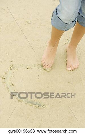 Low section view of a woman drawing in sand with her toe View Large Photo Image Stock Image - Low section view of a woman drawing in sand with her toe. Fotosearch