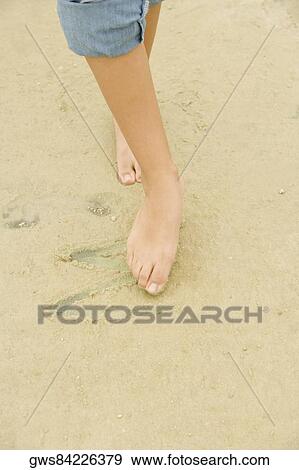 Low section view of a woman drawing in sand with her toe View Large Photo Image Stock Photo - Low section view of a woman drawing in sand with her toe. Fotosearch