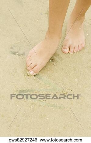 Low section view of a woman drawing in sand with her toe View Large Photo Image Stock Photograph - Low section view of a woman drawing in sand with her toe. Fotosearch