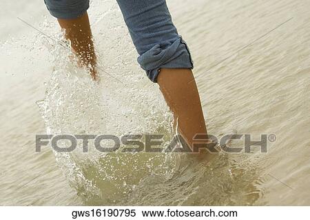 Low section view of a woman kicking water on the beach View Large Photo Image Stock Photography - Low section view of a woman kicking water on the beach. Fotosearch