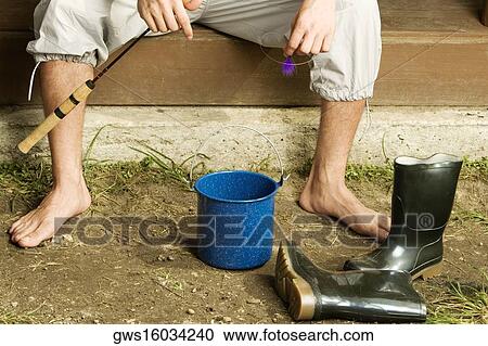 Low section view of a young man sitting on the porch with a bucket and a pair of boots View Large Photo Image Stock Image - Low section view of a young man sitting on the porch with a bucket and a pair of boots. Fotosearch