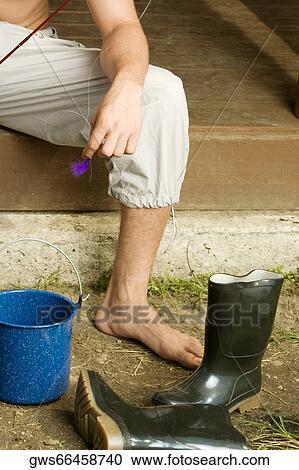 Low section view of a young man sitting on the porch with a bucket and a pair of boots View Large Photo Image Stock Image - Low section view of a young man sitting on the porch with a bucket and a pair of boots. Fotosearch