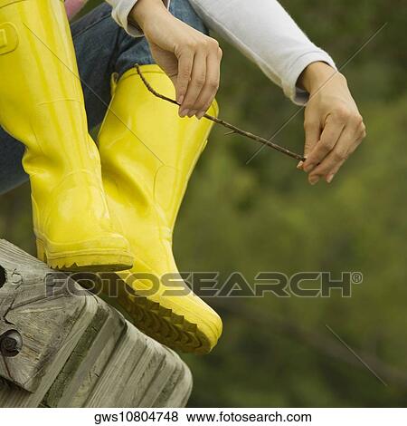 Stock Photo - Low section view of a young woman sitting on a park bench holding a stick. Fotosearch