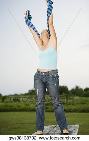 Stock Image - Mature woman standing on the table with her arms outstretched. Fotosearch