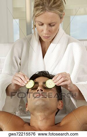 Message therapist putting slices of cucumber on a young man's eyes View Large Photo Image Stock Photograph - Message therapist putting slices of cucumber on a young man's eyes. Fotosearch