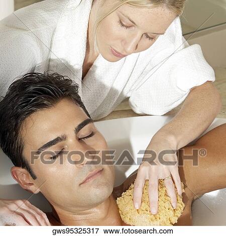 Stock Photo - Message therapist rubbing a bath sponge on a young man's body. Fotosearch
