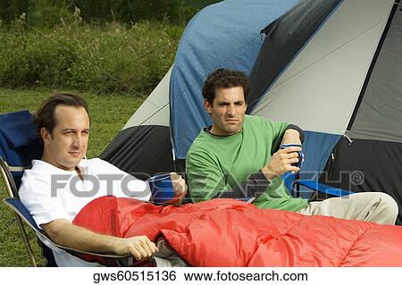 Mid adult man and a mature man holding mugs and resting in front of a tent View Large Photo Image Stock Photograph - Mid adult man and a mature man holding mugs and resting in front of a tent. Fotosearch
