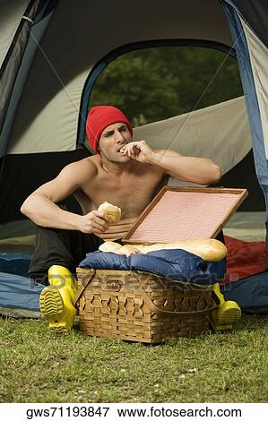 Mid adult man eating a bun sitting in a dome tent View Large Photo Image Stock Photo - Mid adult man eating a bun sitting in a dome tent. Fotosearch