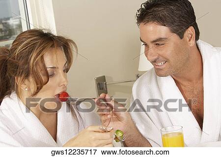 Stock Photo - Mid adult man feeding a mid adult woman a strawberry. Fotosearch