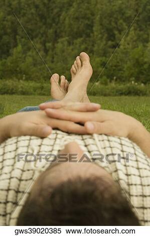 Stock Photography - Mid adult man lying on the grass. Fotosearch