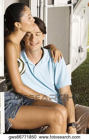 Stock Image - Mid adult man sitting with his arm around a young woman. Fotosearch