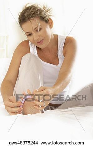 Mid adult woman adjusting her toenail divider View Large Photo Image Picture - Mid adult woman adjusting her toenail divider. Fotosearch