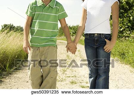 Mid section view of a boy and a girl standing holding hands View Large Photo Image Stock Photography - Mid section view of a boy and a girl standing holding hands. Fotosearch