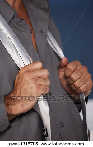 Mid section view of a businessman holding a tie around his neck View Large Photo Image Stock Photography - Mid section view of a businessman holding a tie around his neck. Fotosearch