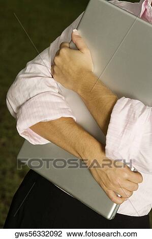 Mid section view of a businesswoman holding a laptop View Large Photo Image Stock Image - Mid section view of a businesswoman holding a laptop. Fotosearch