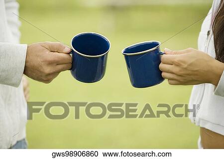 Mid section view of a couple holding two cups View Large Photo Image Stock Image - Mid section view of a couple holding two cups. Fotosearch