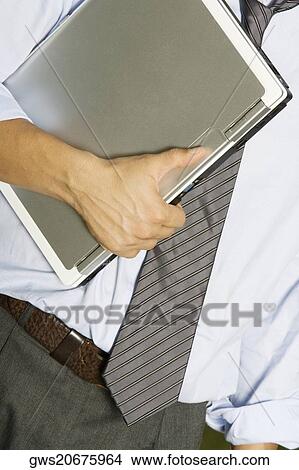 Mid section view of a man holding a laptop View Large Photo Image Picture - Mid section view of a man holding a laptop. Fotosearch