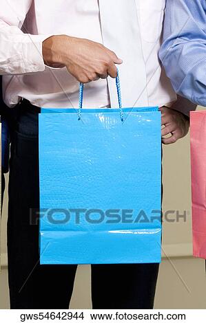 Picture - Mid section view of a man holding a shopping bag. Fotosearch