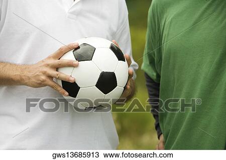 Mid section view of a man holding a soccer ball View Large Photo Image Stock Image - Mid section view of a man holding a soccer ball. Fotosearch